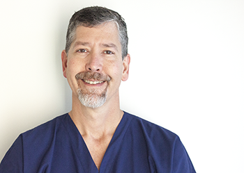 Dr. John smiles against a white background.