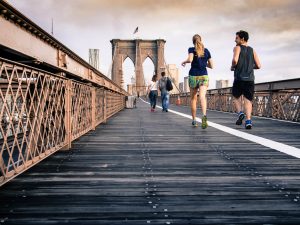 A group of people run along a wooden bridge.