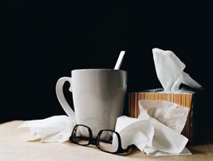 Cold and flu at its worst in a cluster of used tissue, eyeglasses and a mug.